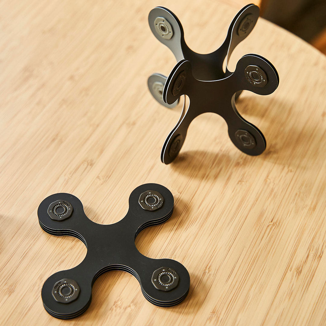 Clixo magnetische bouwset, losse zwarte en grijze elementen en een kleine constructie op een houten tafel.