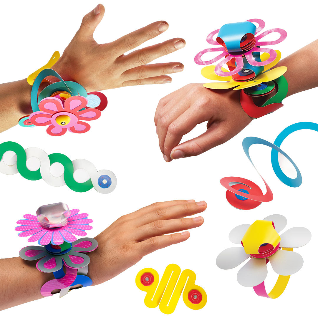 Verschillende handen dragen Clixo magnetische sieraden, zoals armbanden en ringen, gemaakt van de kleurrijke bouwstukken.