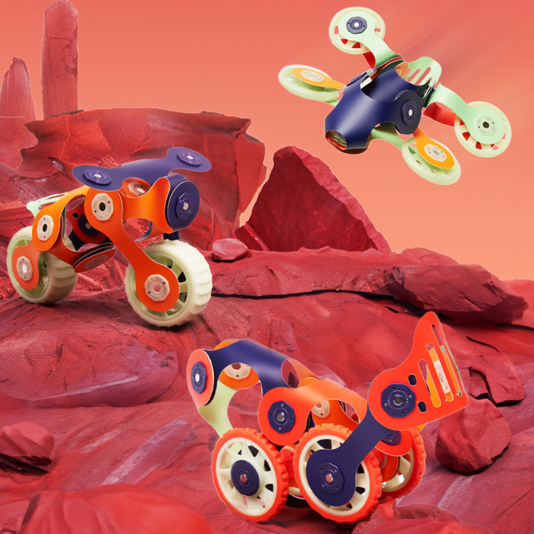 Drie Clixo bouwset modellen, een motor, een rover en een drone, op een rood Mars-landschap.