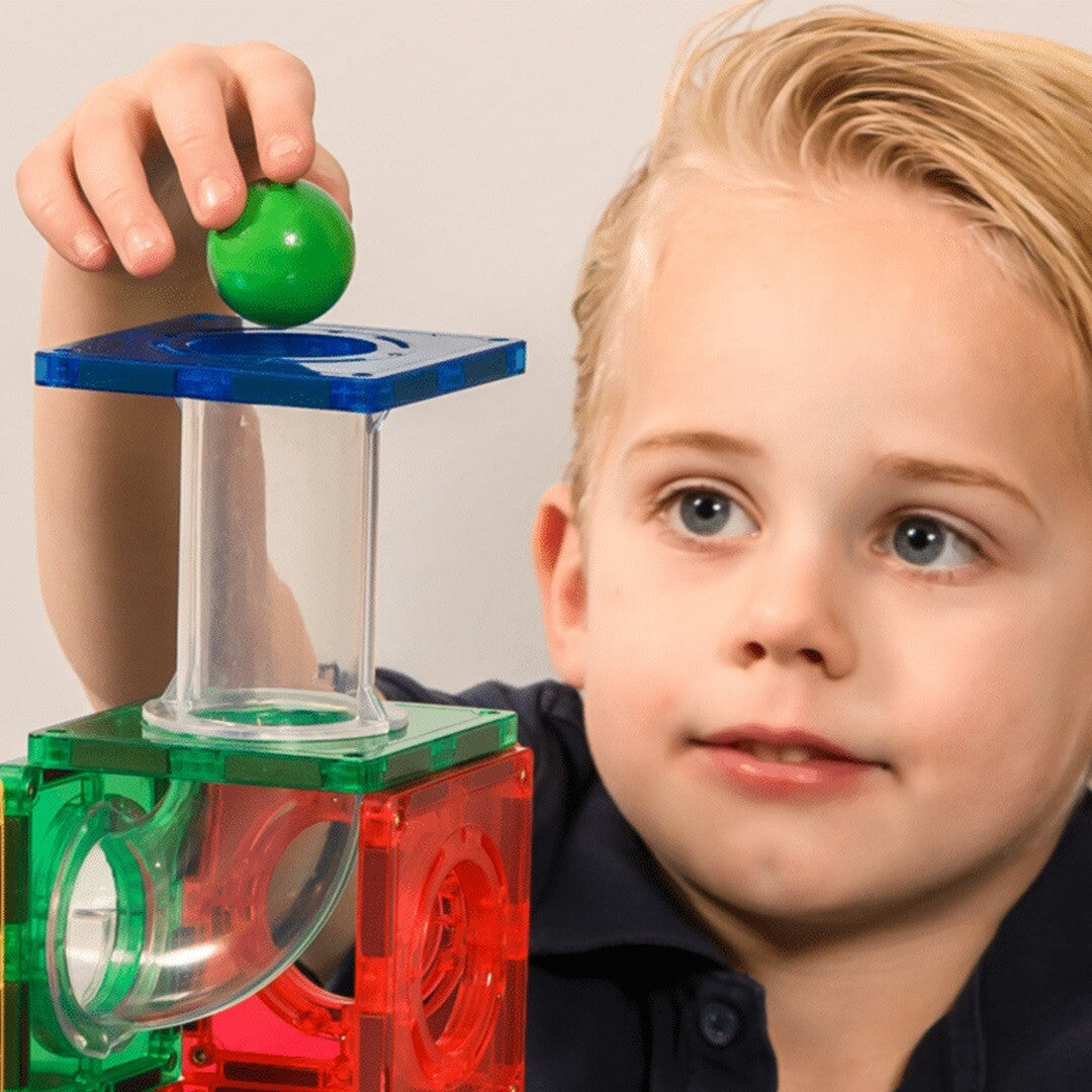 Een kind plaatst een groene knikkerbaanbal in een Coblo knikkerbaan.