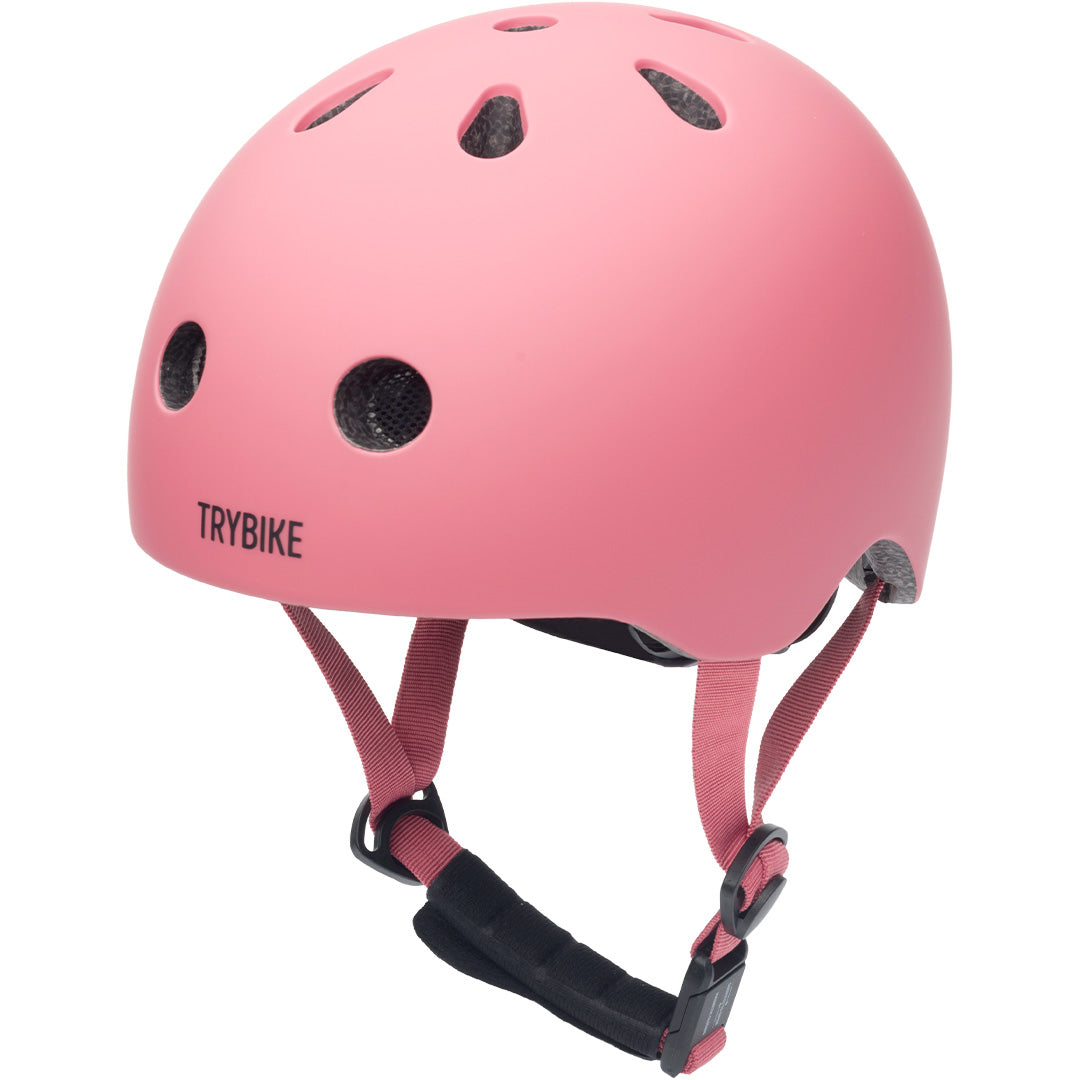 Een roze kinderhelm van coconuts helmets, schuin gefotografeerd.