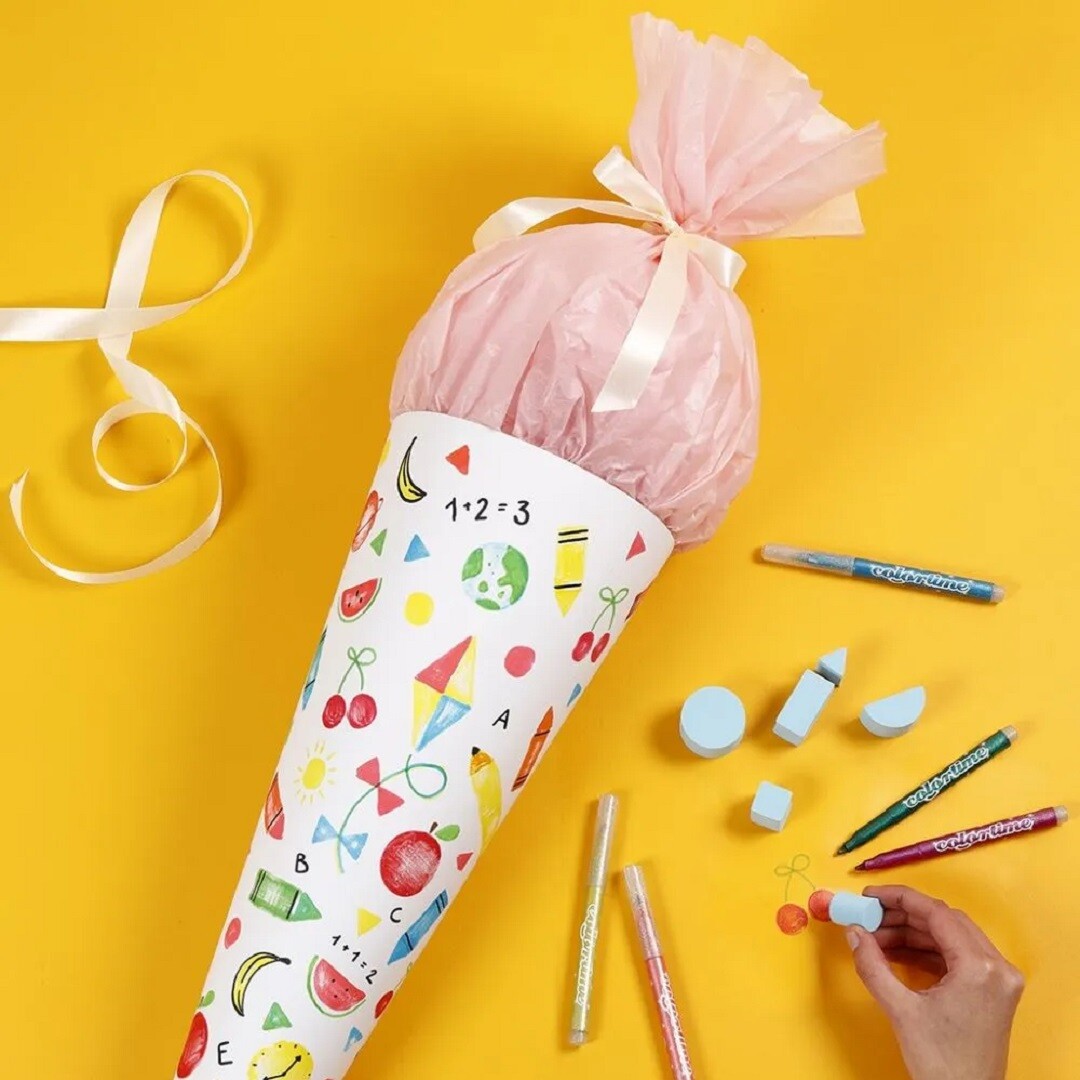 Een gedecoreerde schooltas met roze vulling, omringd door colortime glitter markers en gummen op een gele achtergrond.