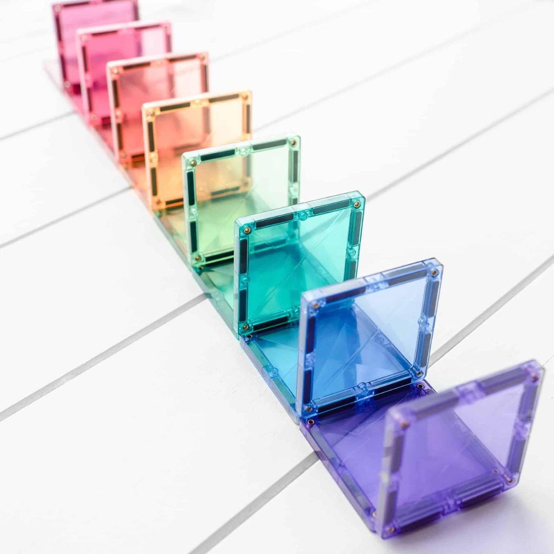 Een rij van Connetix pastel magnetische tegels in regenboogkleuren, staand op een witte ondergrond.