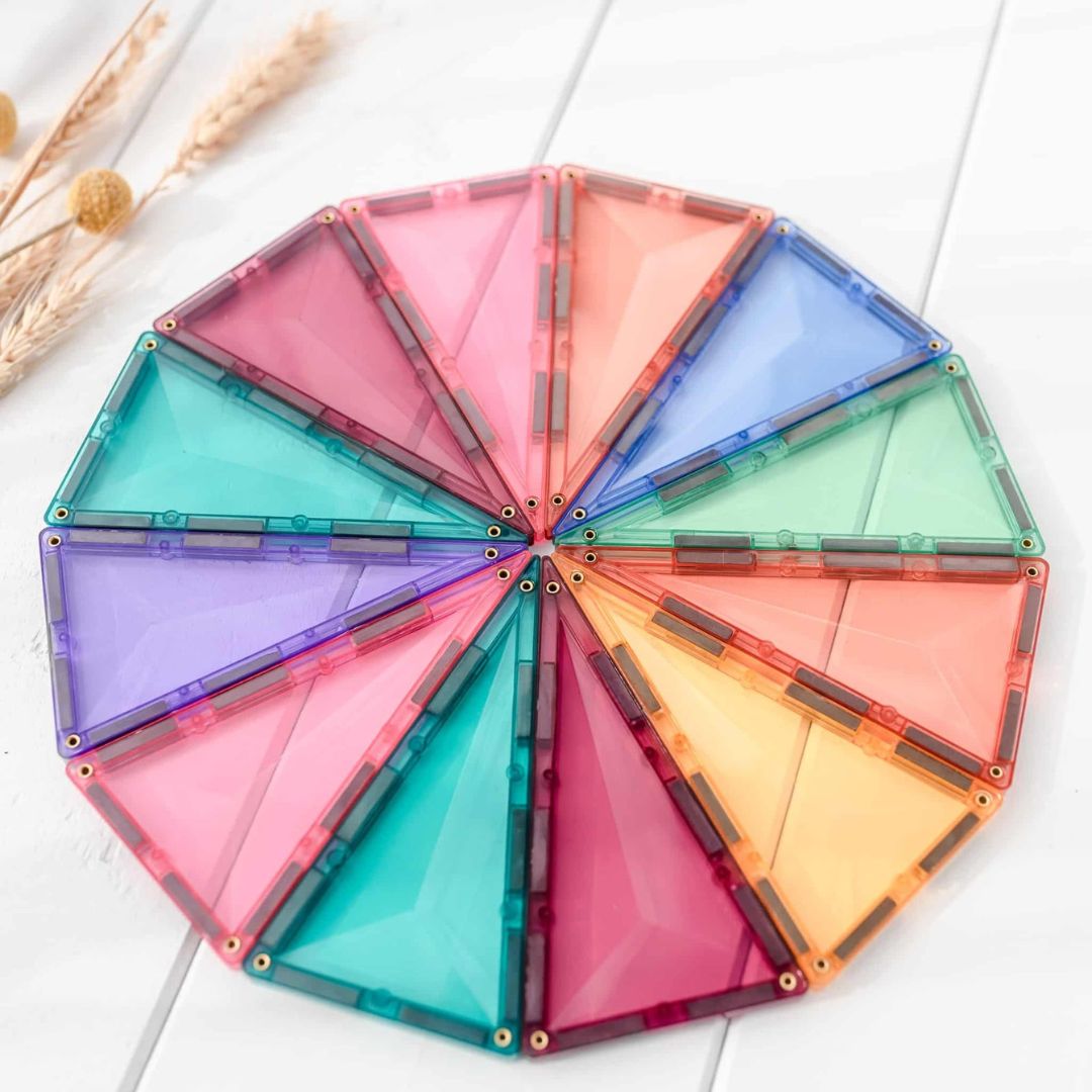 Een cirkelvormig patroon van Connetix pastel magnetische driehoekige tegels op een witte ondergrond.