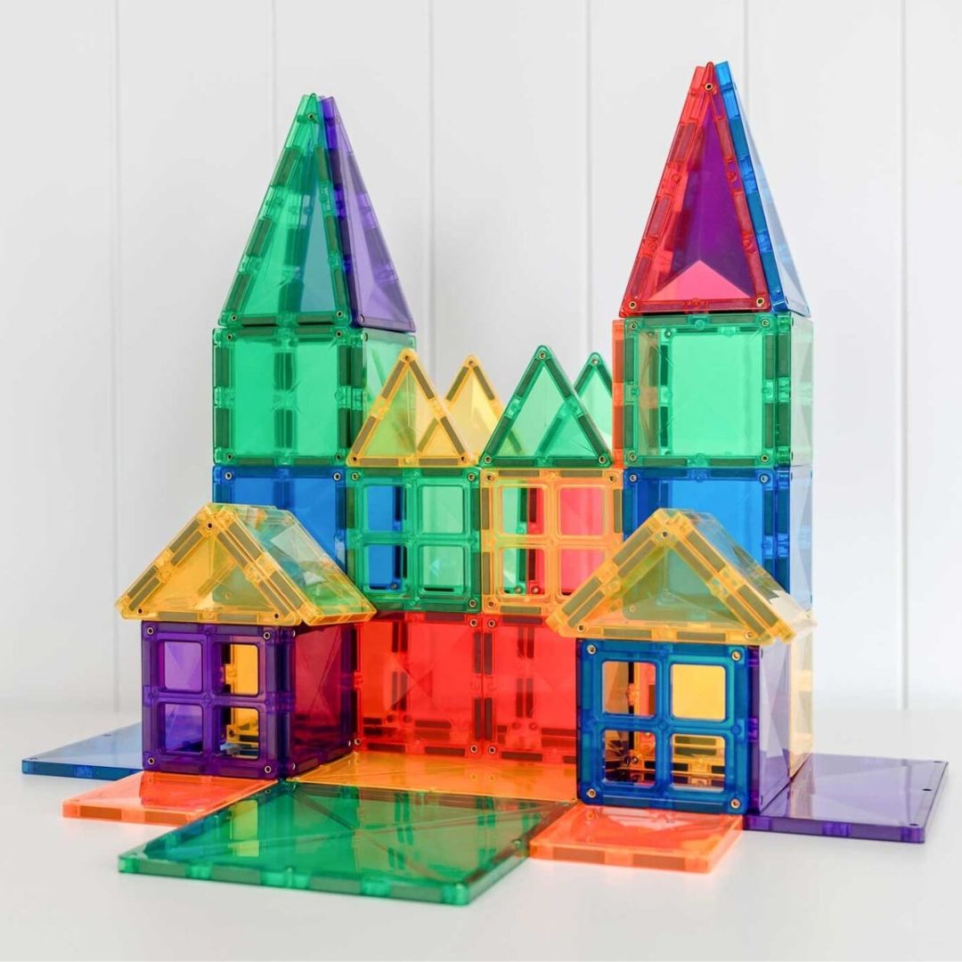 Een kleurrijk kasteel met kleine huisjes, gebouwd van Connetix magnetische tegels.
