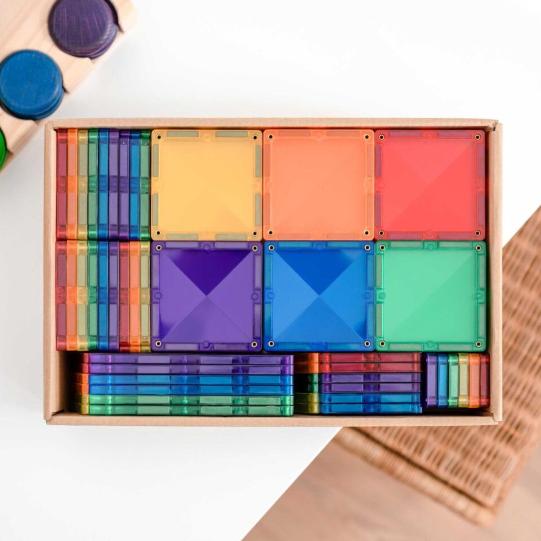 Een open doos met netjes gestapelde Connetix magnetische tegels in regenboogkleuren.