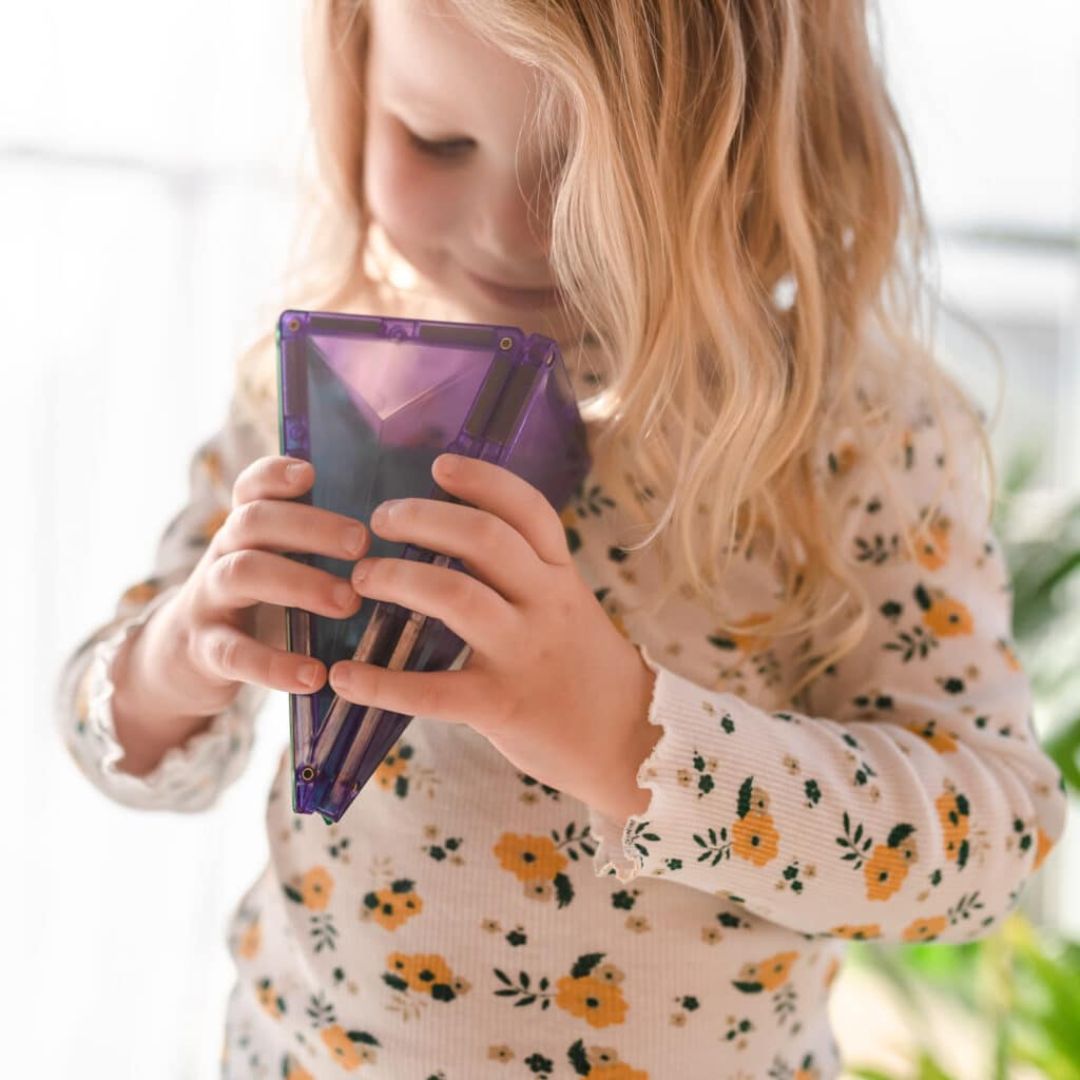 Een kind houdt een paarse 3D-vorm vast, gemaakt van Connetix magnetische tegels.