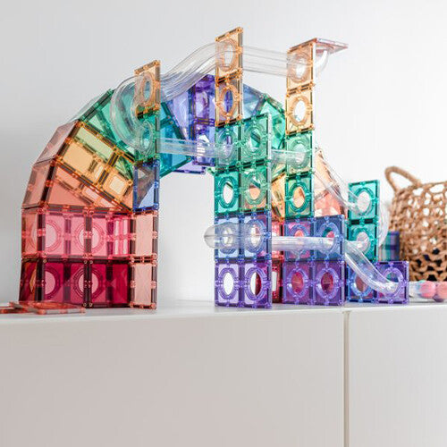 Een grote, kleurrijke Connetix magnetische tegels knikkerbaan in pastelkleuren, gebouwd op een witte kast.