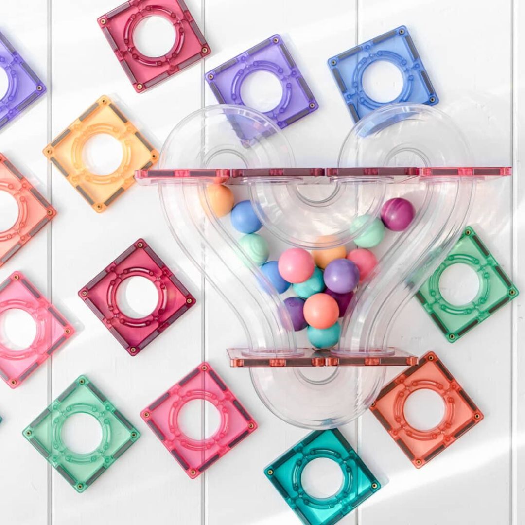 Bovenaanzicht van een Connetix magnetische tegels knikkerbaan met pastelkleurige ballen in een trechter.