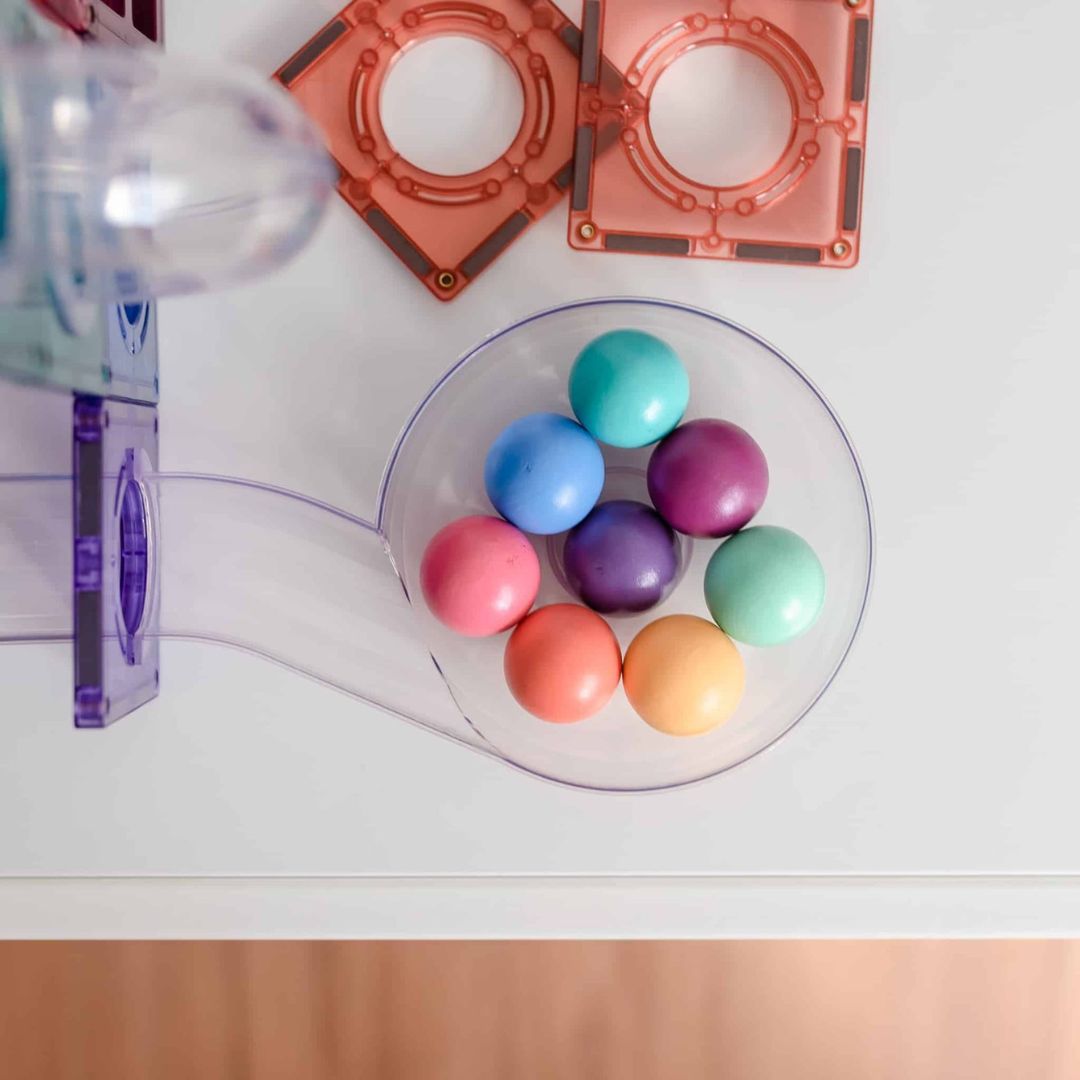 Detail van pastelkleurige ballen die verzameld zijn in een transparant onderdeel van de Connetix knikkerbaan.