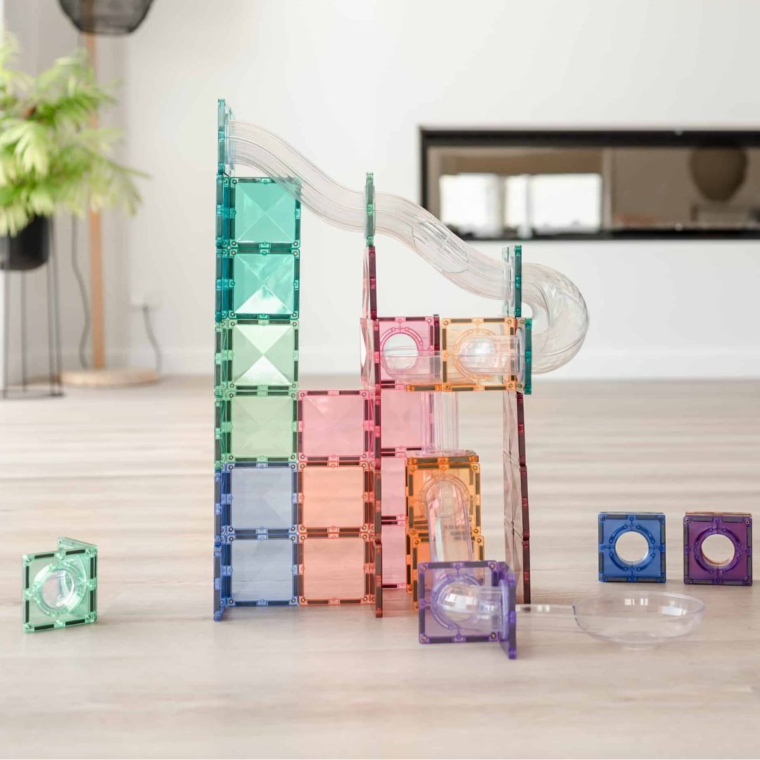 Een opgebouwde Connetix pastel knikkerbaan van magnetische tegels en transparante buizen op een lichte vloer.