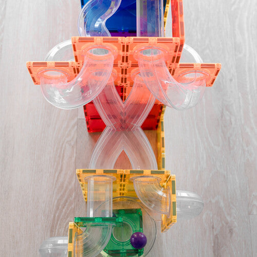 Detail van een Connetix knikkerbaan met oranje en rode magnetische tegels en transparante bochten.