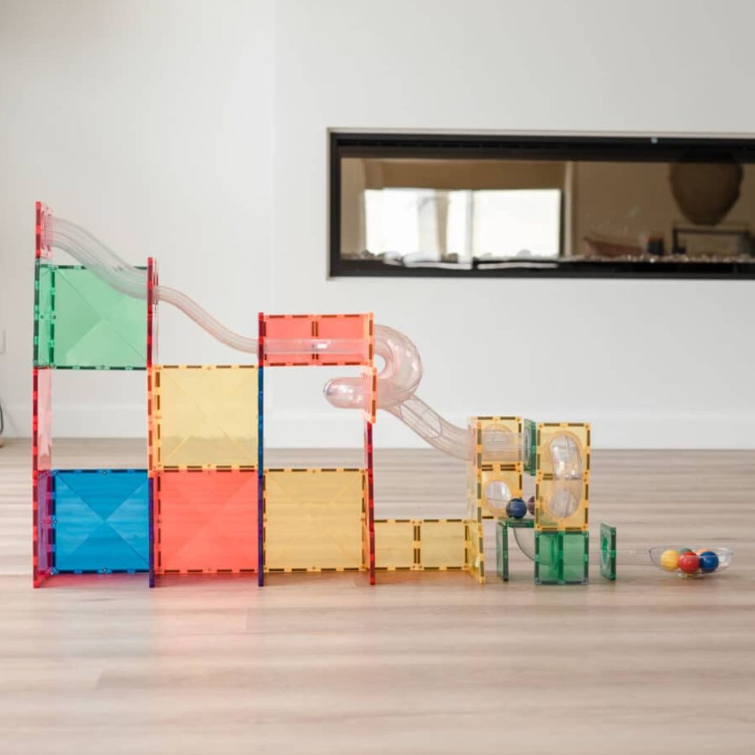 Een complete Connetix regenboog knikkerbaan van magnetische tegels op een houten vloer.