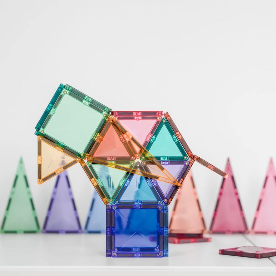 Een abstracte constructie van Connetix magnetische tegels in pastelkleuren, met losse tegels op de achtergrond.
