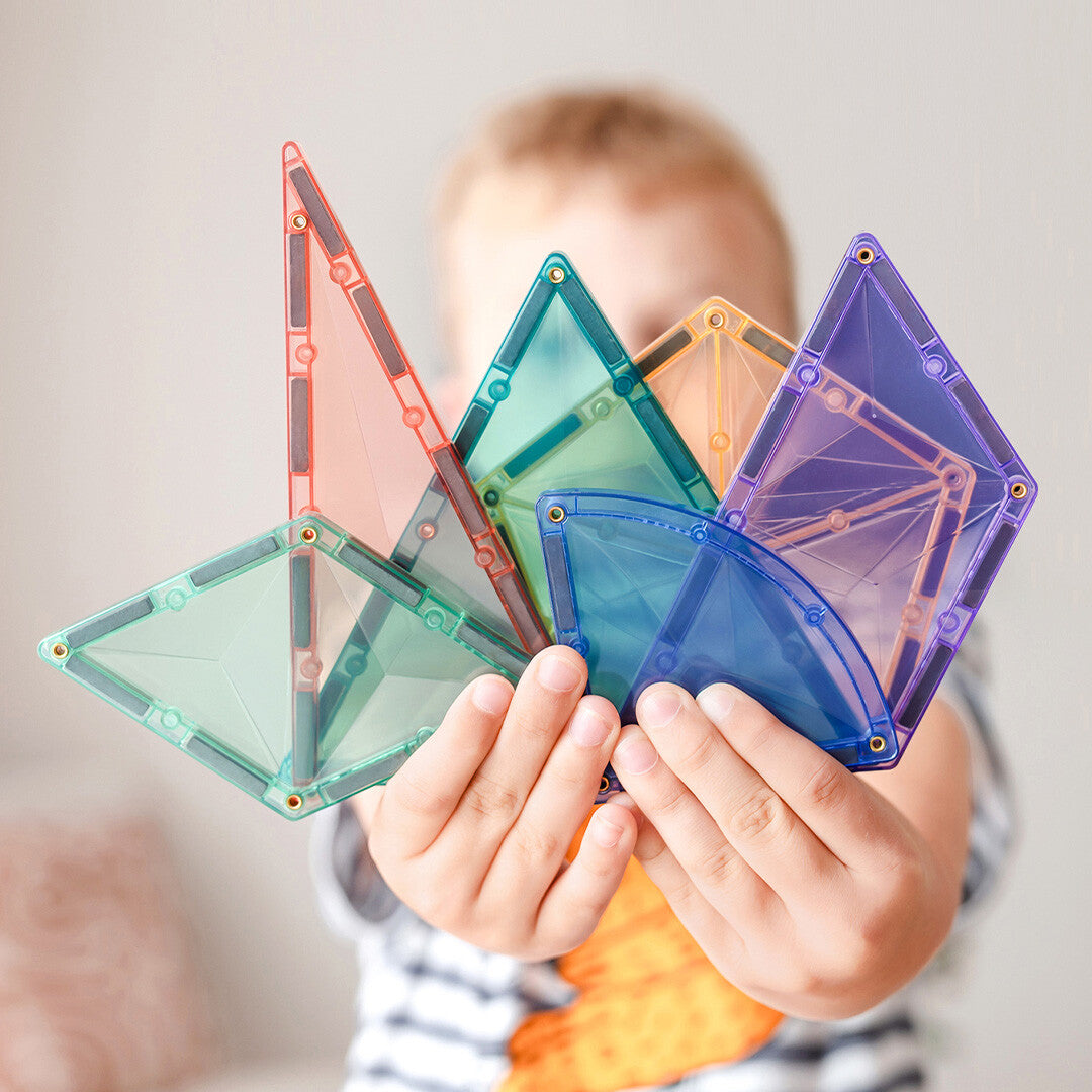 Kinderhanden houden een waaier van Connetix pastel magnetische tegels vast.