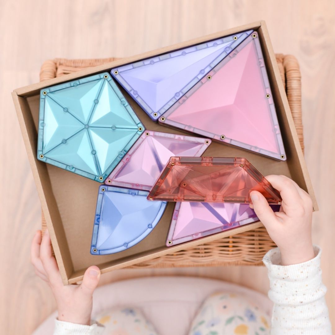 Kinderhanden pakken een Connetix pastel magnetische tegel uit de productdoos.