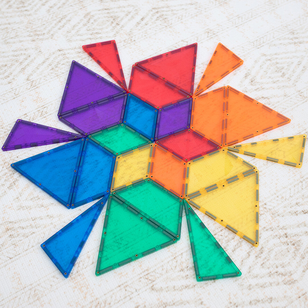 Verschillende Connetix magnetische tegels in regenboogkleuren liggen plat op een witte ondergrond.