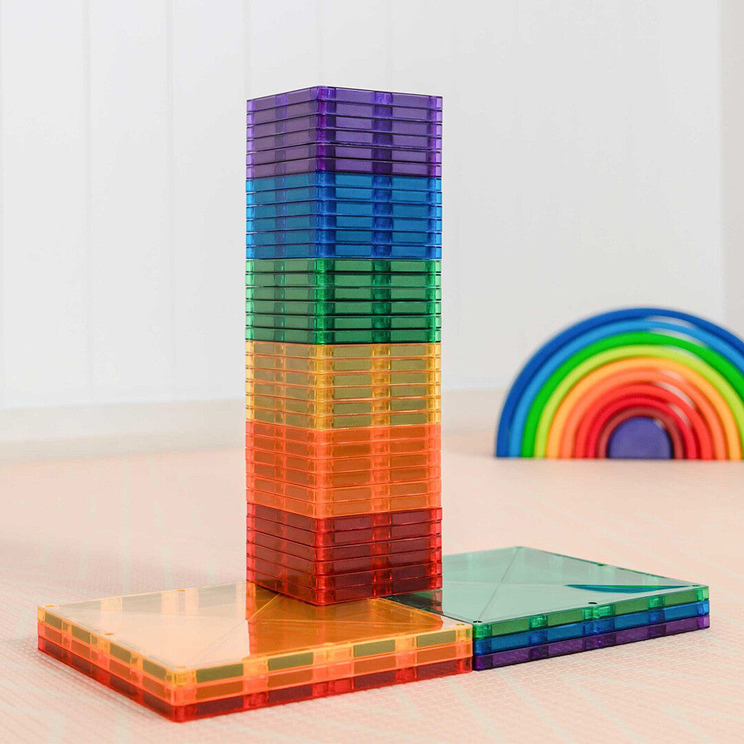 Een hoge toren van Connetix magnetische tegels in regenboogkleuren, met een regenboogboog op de achtergrond.