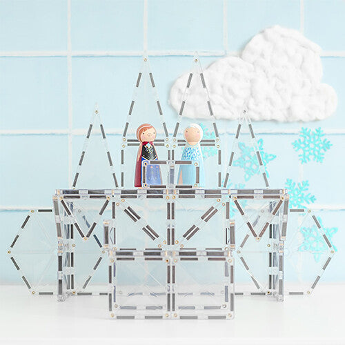 Een ijskasteel gebouwd met Connetix transparante magnetische tegels, met twee houten poppetjes en winterdecoratie op de achtergrond.