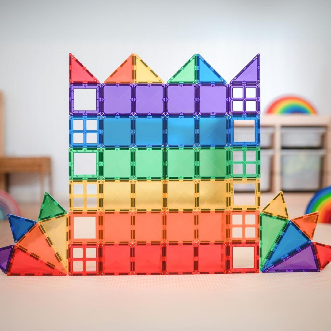 Een muurachtige constructie in regenboogkleuren, gebouwd met Connetix magnetische tegels.