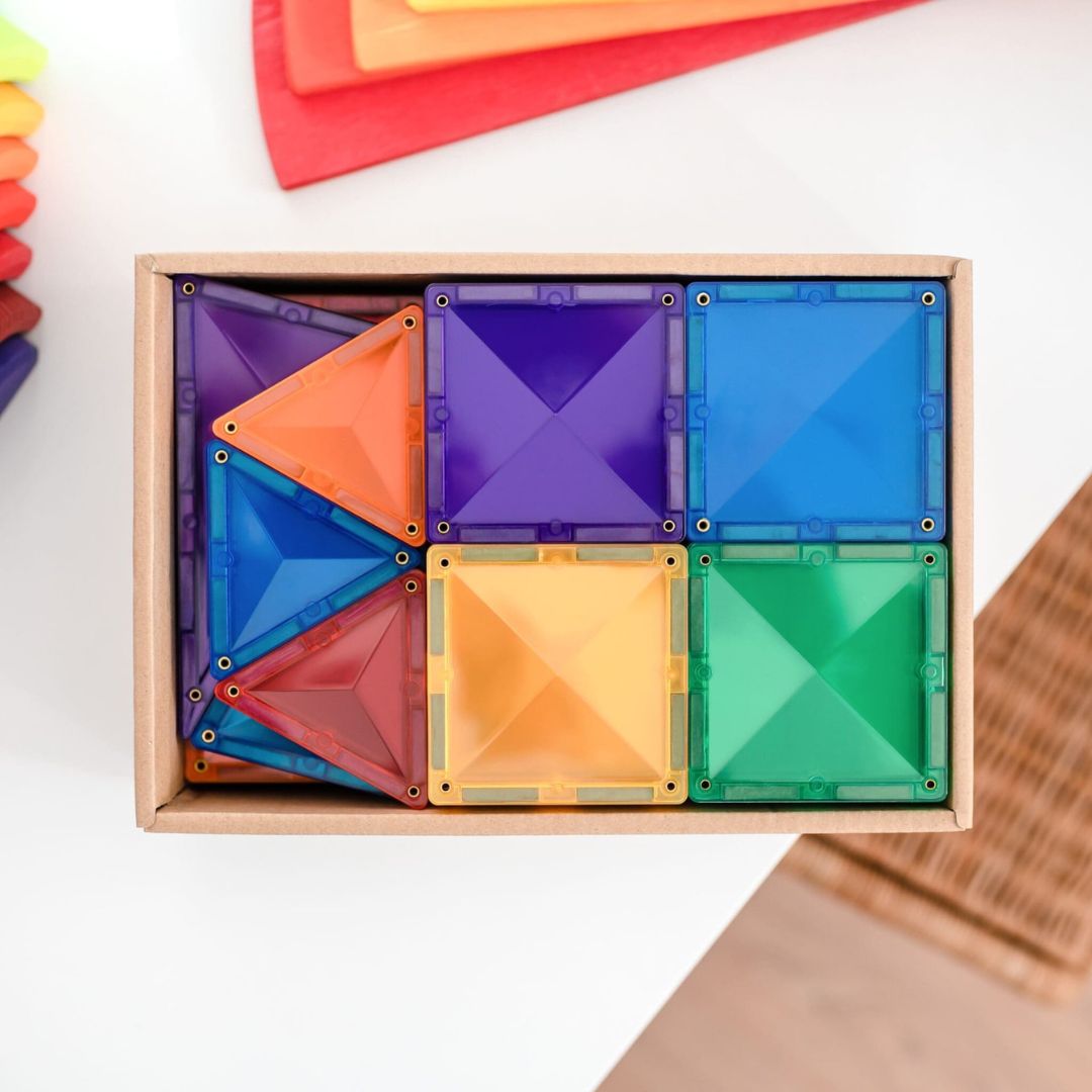 Een open doos met Connetix magnetische tegels in verschillende kleuren en vormen, van bovenaf gezien.