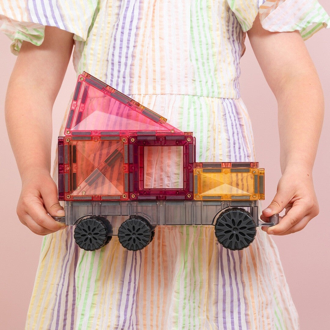 Een kind houdt een Connetix vrachtwagen vast, gemaakt van pastelkleurige magnetische tegels.