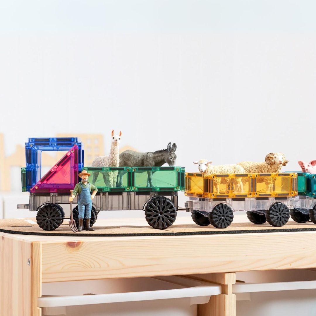 Een Connetix trein, gemaakt van pastelkleurige magnetische tegels, vervoert speelgoedboerderijdieren en een boer.