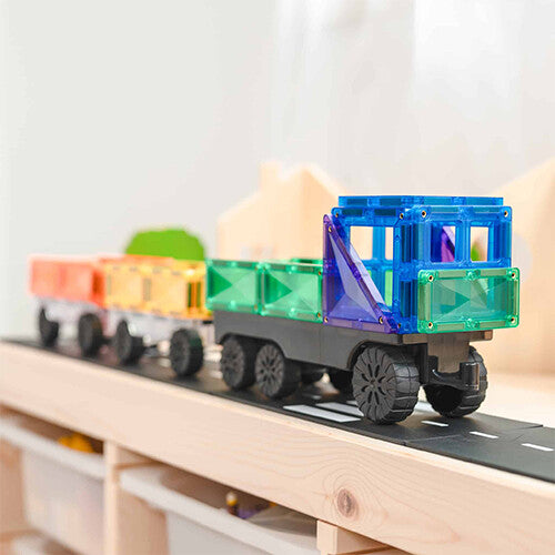 Een Connetix magnetische tegels vrachtwagen met aanhanger vol kleurrijke blokken rijdt op een speelmat.
