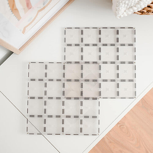 Twee transparante Connetix magnetische bouwplaten liggen plat op een witte tafel.