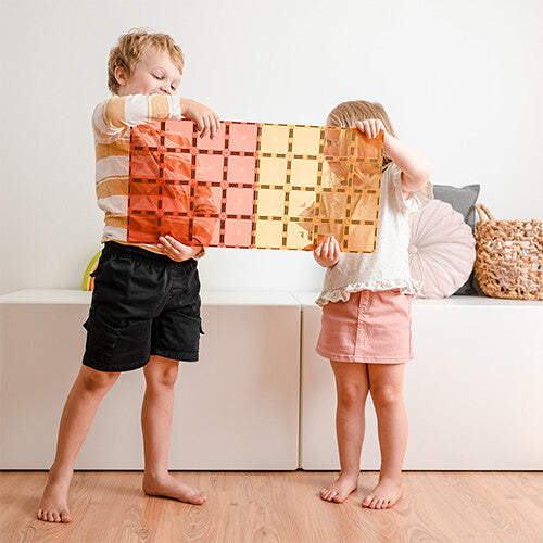 Twee kinderen houden samen twee grote Connetix pastel magnetische bouwplaten vast.