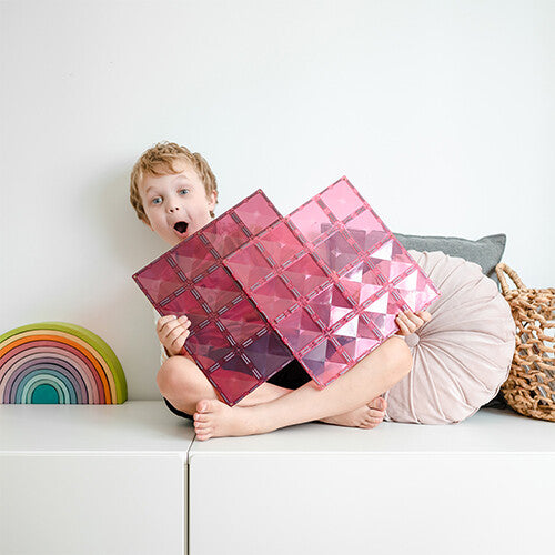 Een kind houdt twee grote Connetix roze en bessenkleurige magnetische bouwplaten vast.