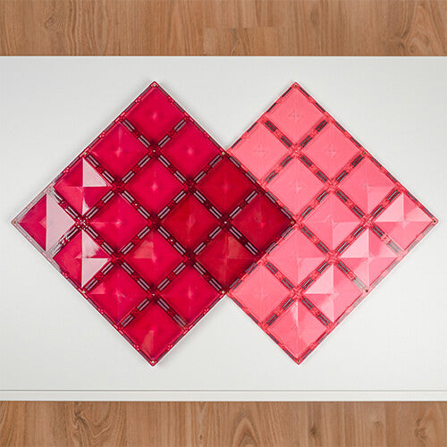 Twee Connetix magnetische bouwplaten in roze en bessenkleur liggen naast elkaar op een witte ondergrond.