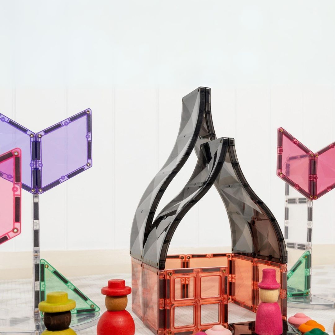 Een huisachtig bouwwerk van zwarte en oranje magnetische tegels met houten poppetjes ervoor.