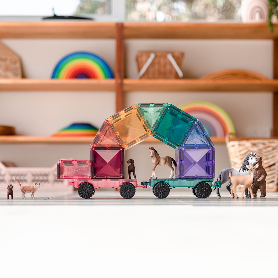 Een trein gebouwd van Connetix pastel magnetische tegels met dierenfiguren erop, op een vloer.