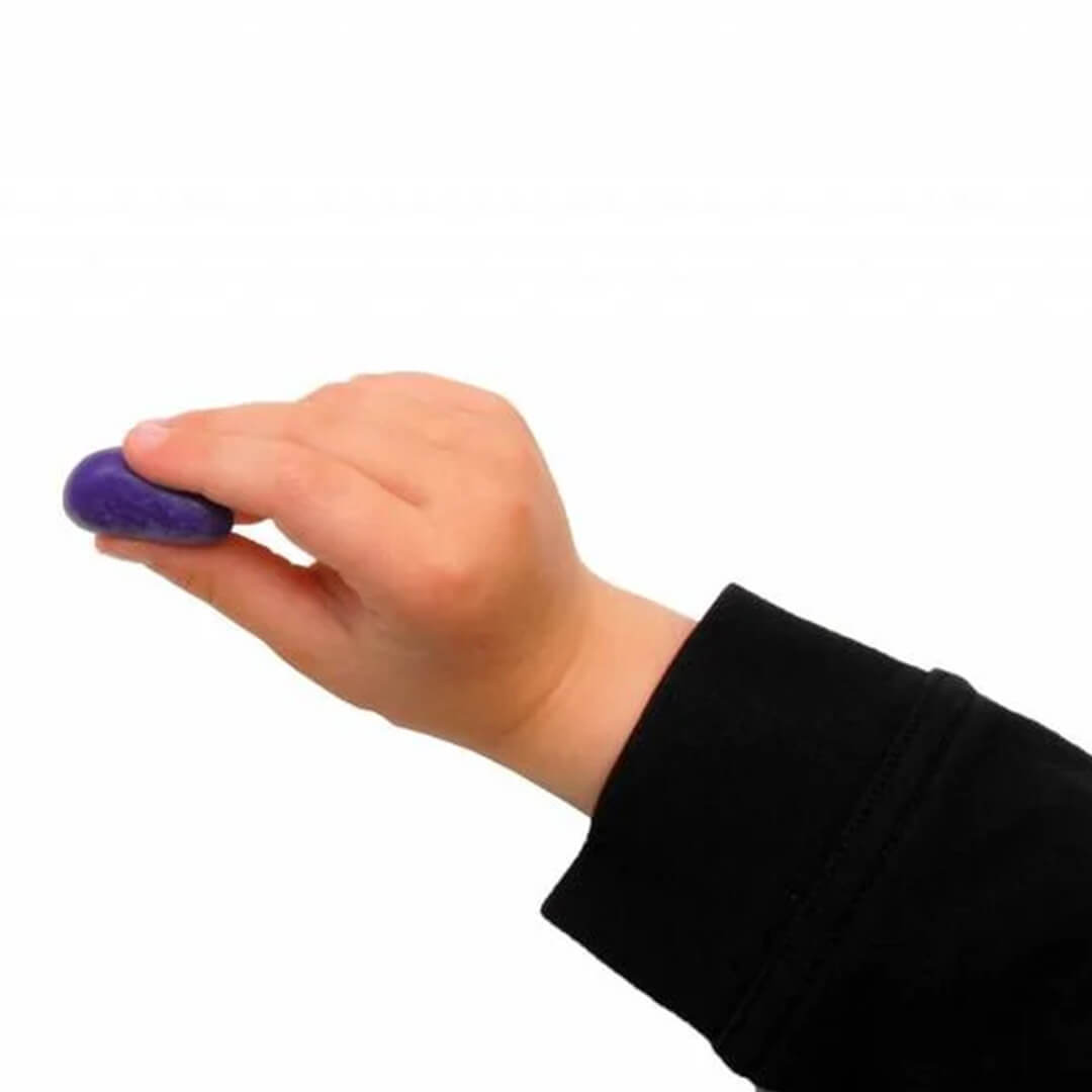 Een kinderhand houdt een paars Crayon Rocks waskrijtje vast, ter demonstratie van de ergonomische vorm.