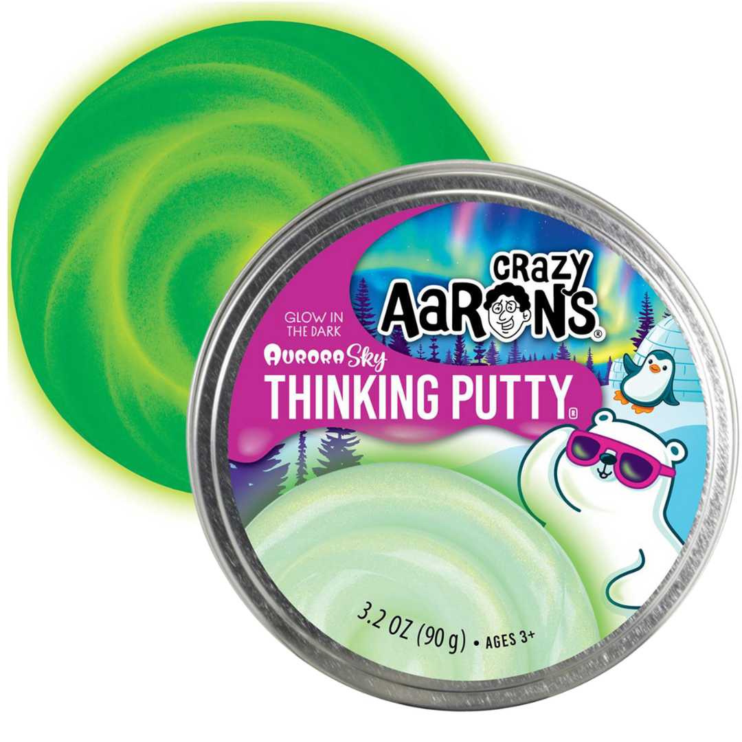 Crazy Aaron's Aurora Sky glow-in-the-dark klei in een blikje, met een groene lichtgevende wervel ernaast.