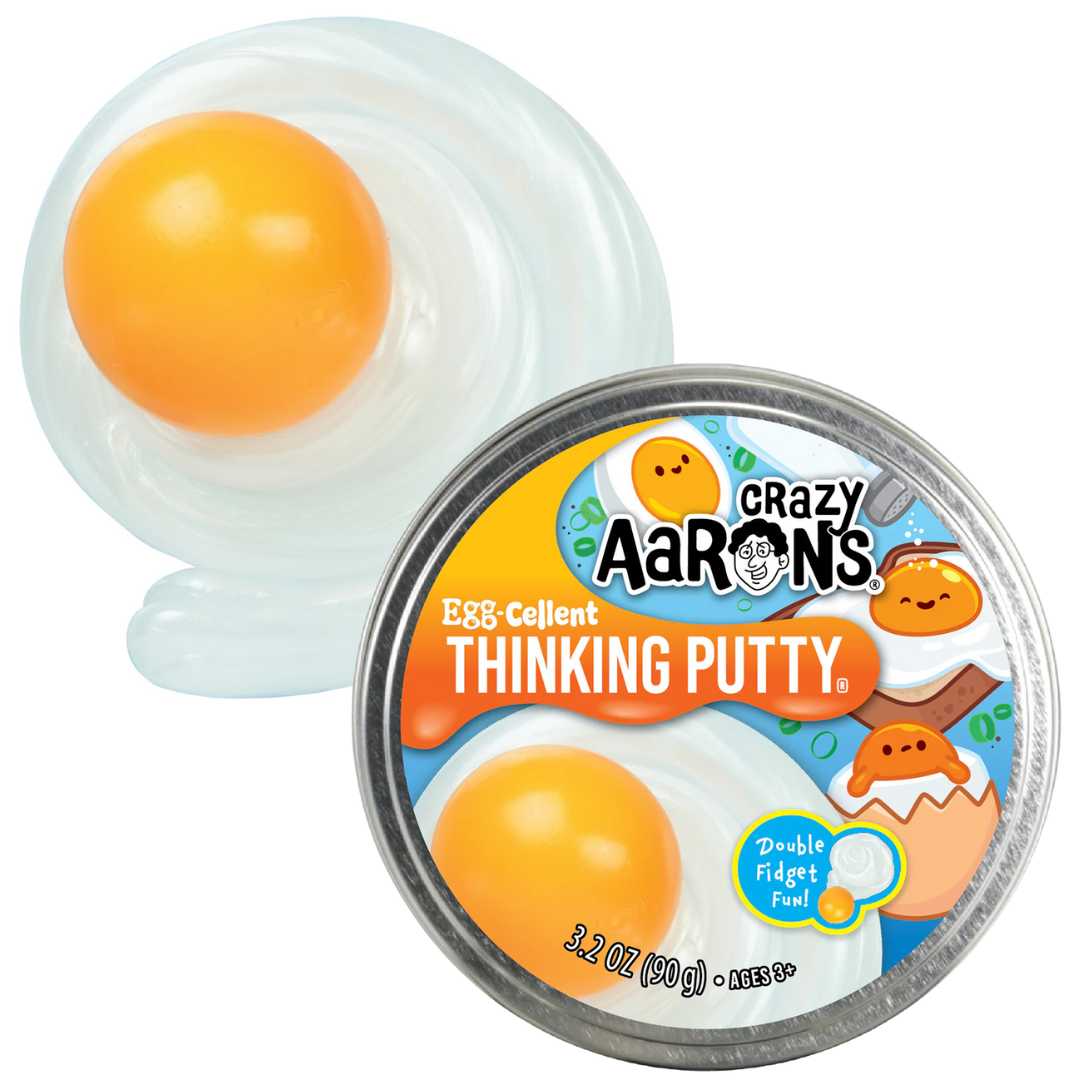 Crazy Aaron's Egg-Cellent Thinking Putty blikje naast de gele dooier en witte eiwitvormige putty.