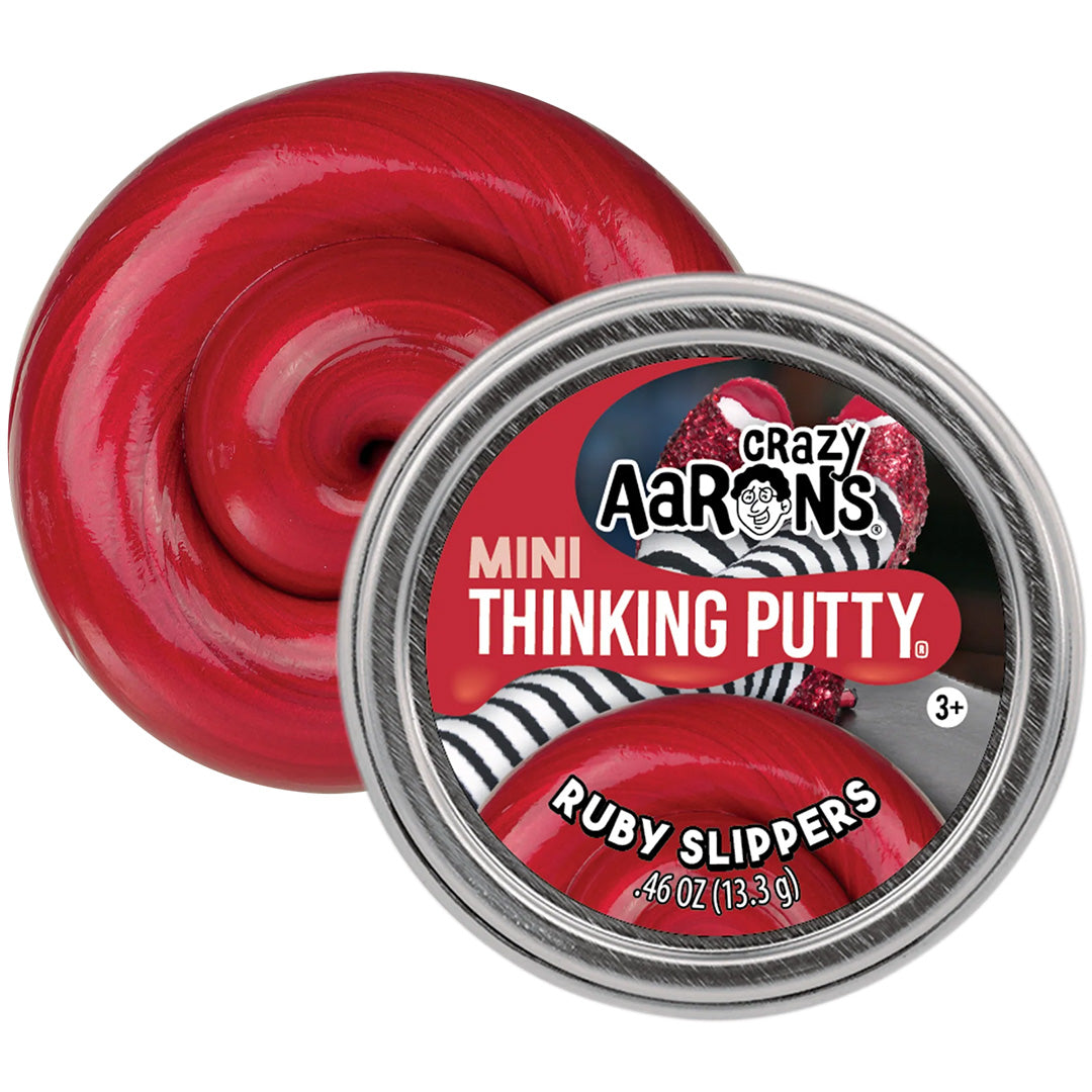 Crazy Aaron's Mini Thinking Putty Ruby Slippers, een rode glimmende klei naast de geopende verpakking.