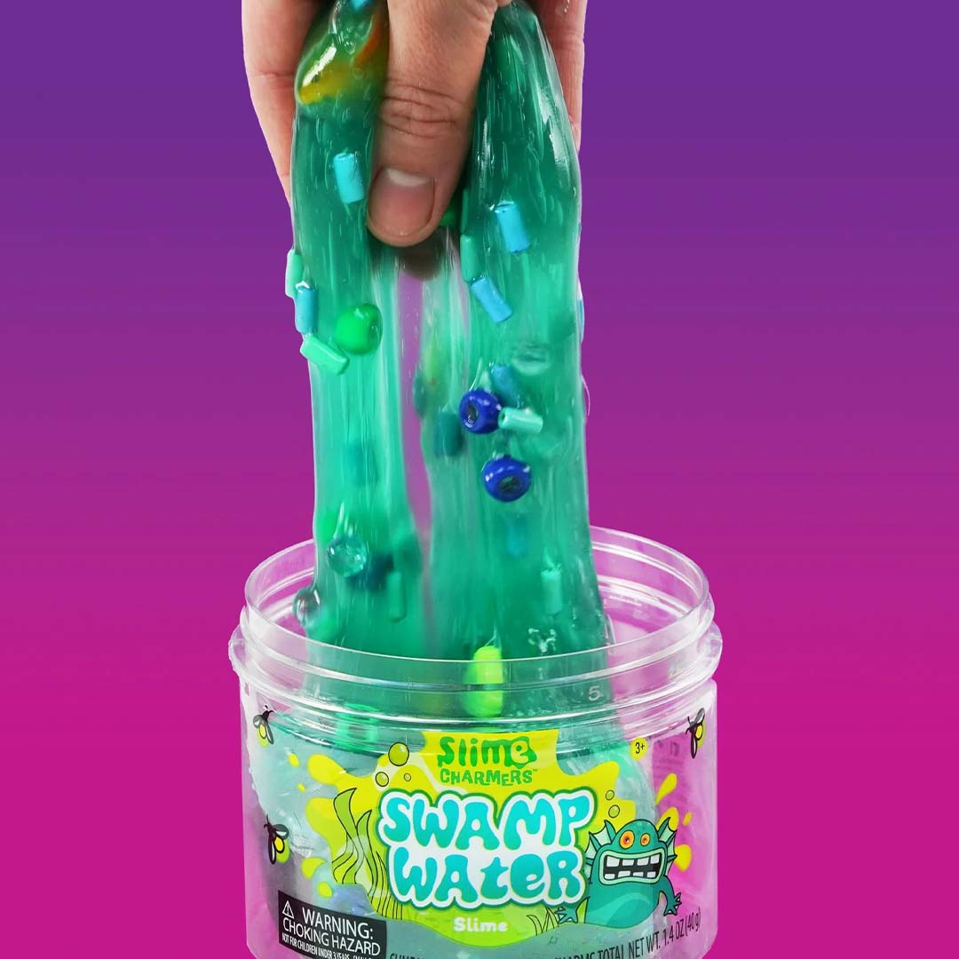 Een hand trekt groen Crazy Aaron's Slime Swamp Water met kleine dierfiguren uit de pot.