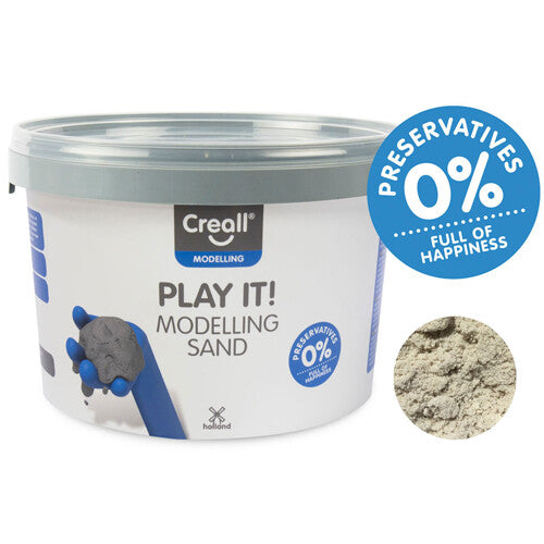 Creall Play It! Modelleerzand in een witte emmer met blauw etiket en een detail van de zandtextuur.