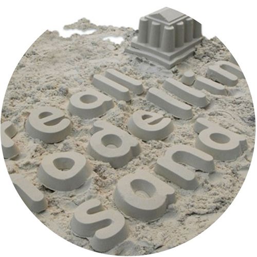 Creall modelleerzand met daarin gevormde letters en een gebouw.