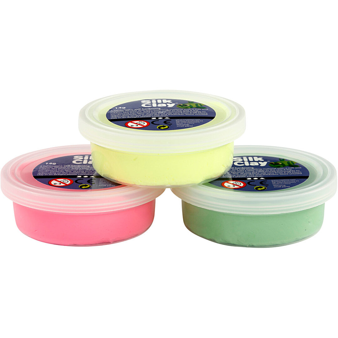 Drie potjes Creativ Company Silk Clay boetseerklei in neon geel, roze en groen, los van elkaar op een rij.