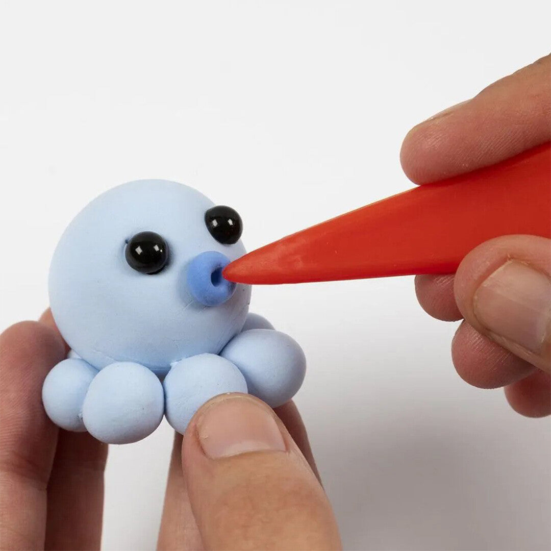 Handen vormen met een rood gereedschap de mond van een blauwe octopus van creativ company Silk Clay.