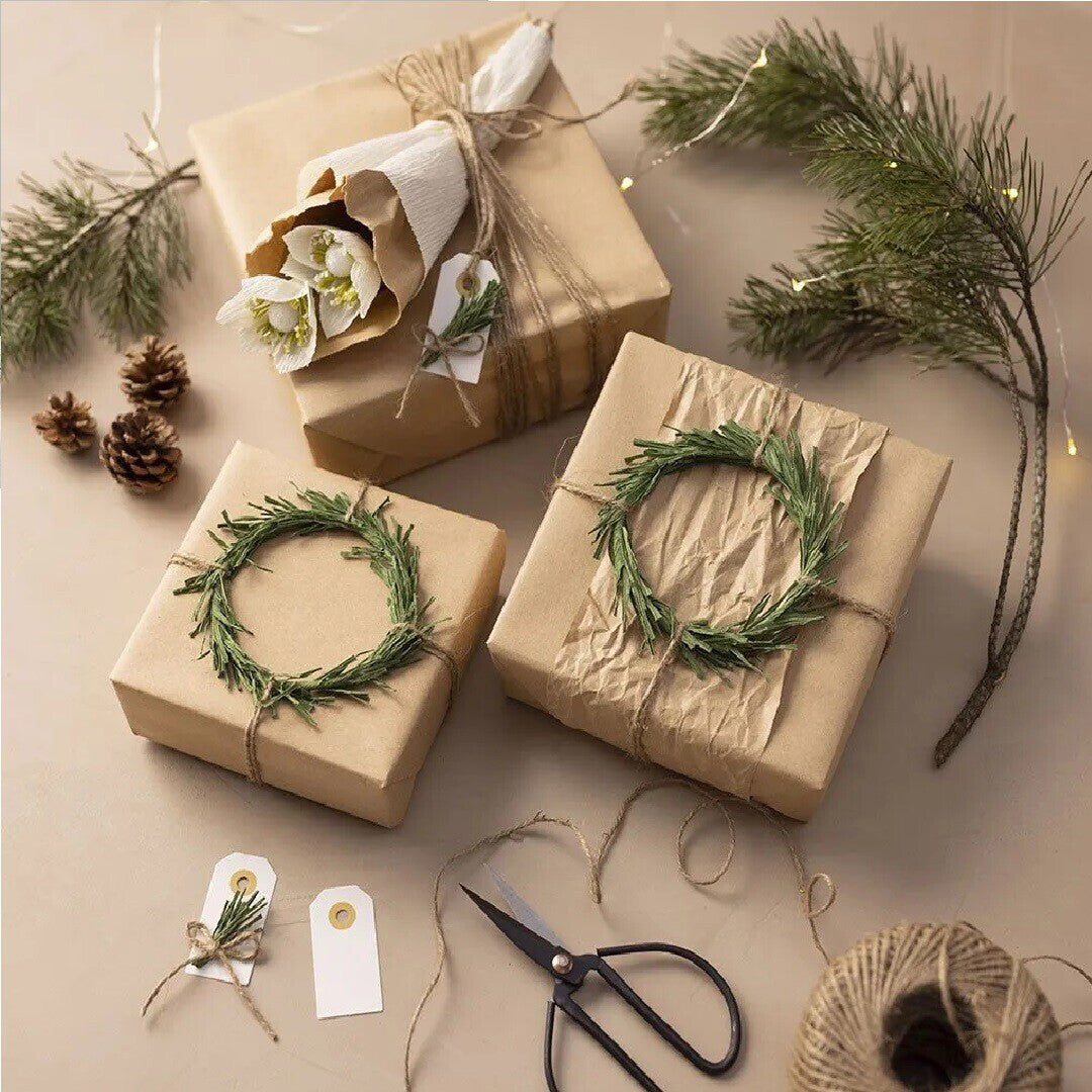 Drie ingepakte cadeaus met rozemarijnkransen, dennentakken en twee crèmekleurige cadeaulabels.