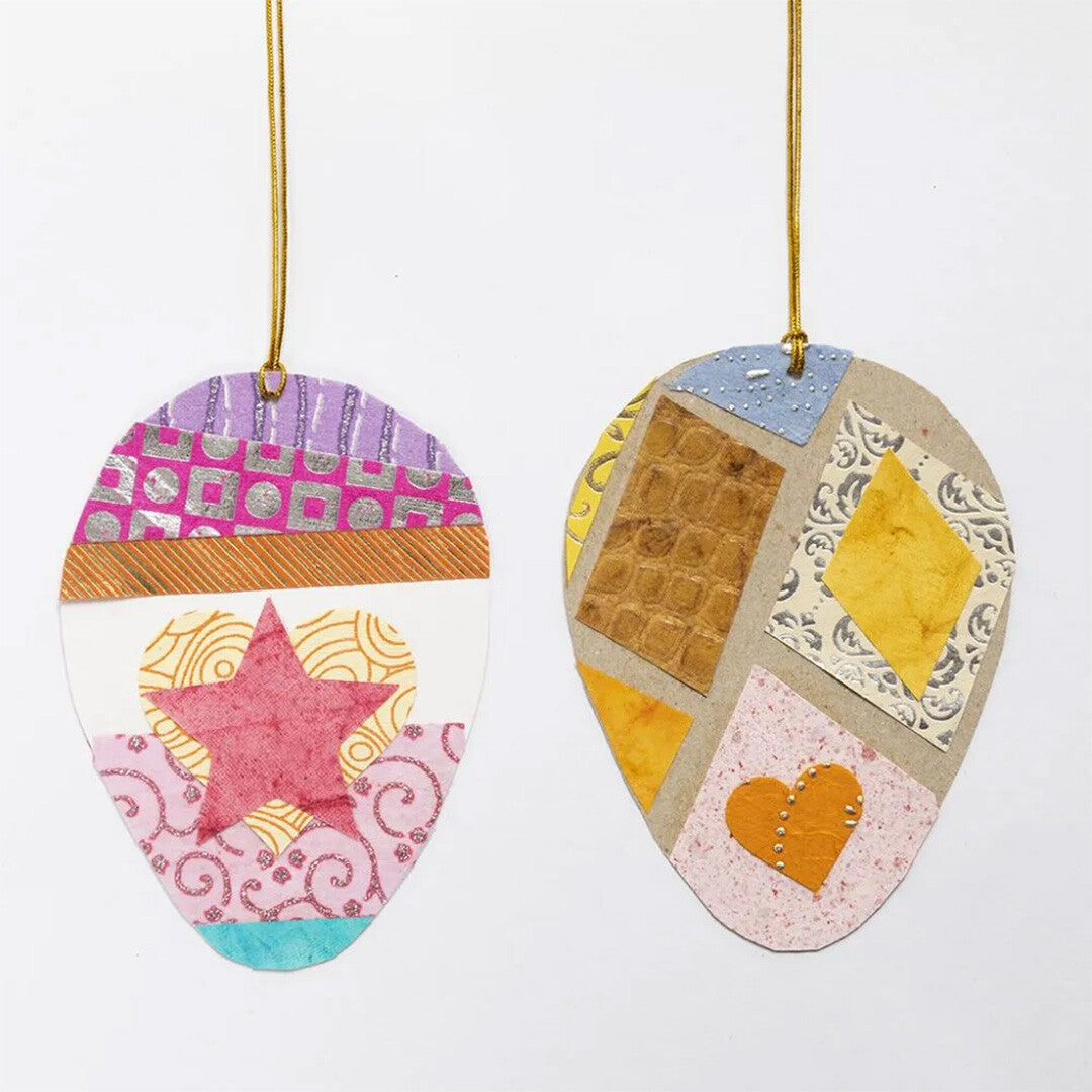 Twee eivormige hangdecoraties gemaakt van creativ company decoratie papiervormen, met een roze ster en een oranje hart.