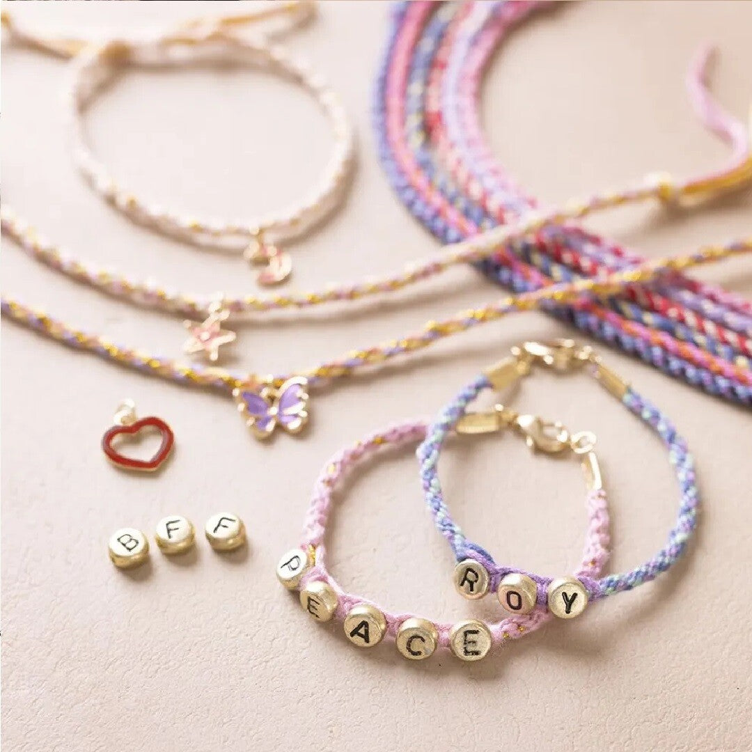 Detail van diverse gevlochten Kumihimo armbandjes met letterkralen die 'PEACE' en 'ROY' spellen, en losse bedels.