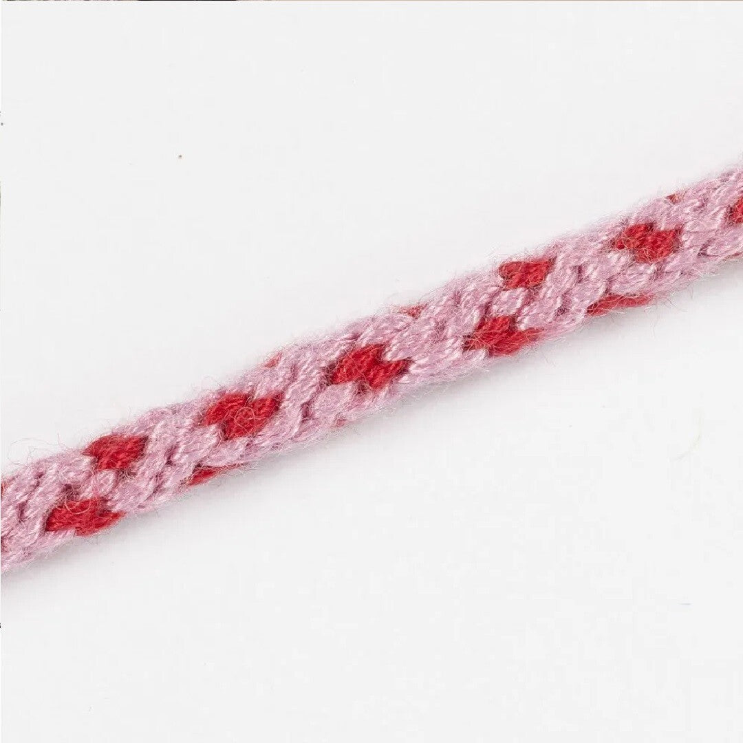 Close-up van een roze gevlochten Kumihimo draad met rood hartjespatroon.
