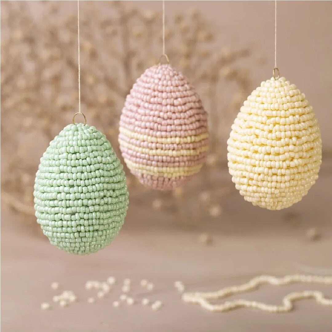 Drie hangende paaseieren versierd met kleine pastelkleurige kraaltjes.