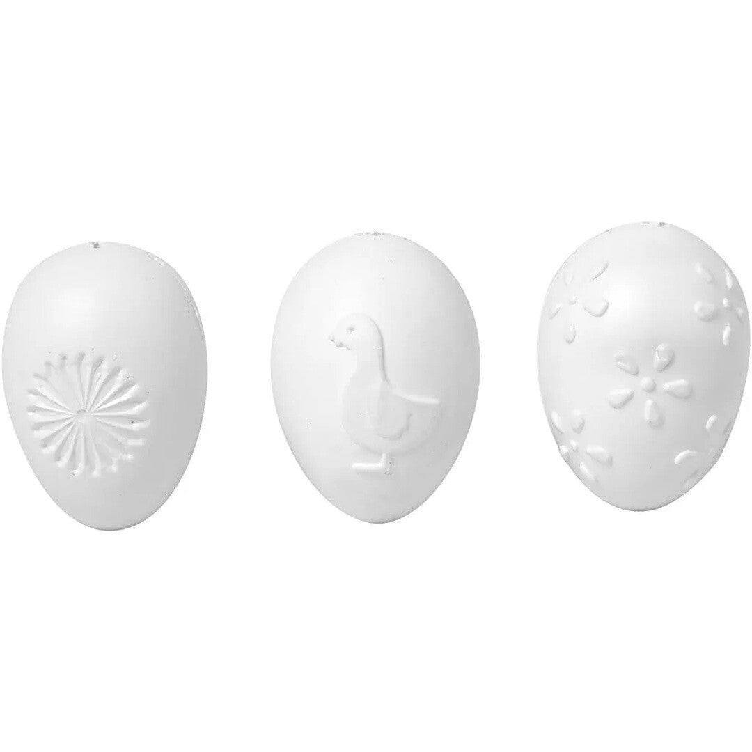 Drie witte Creativ Company paaseieren met verschillende patronen: een ster, een eendje en bloemen.