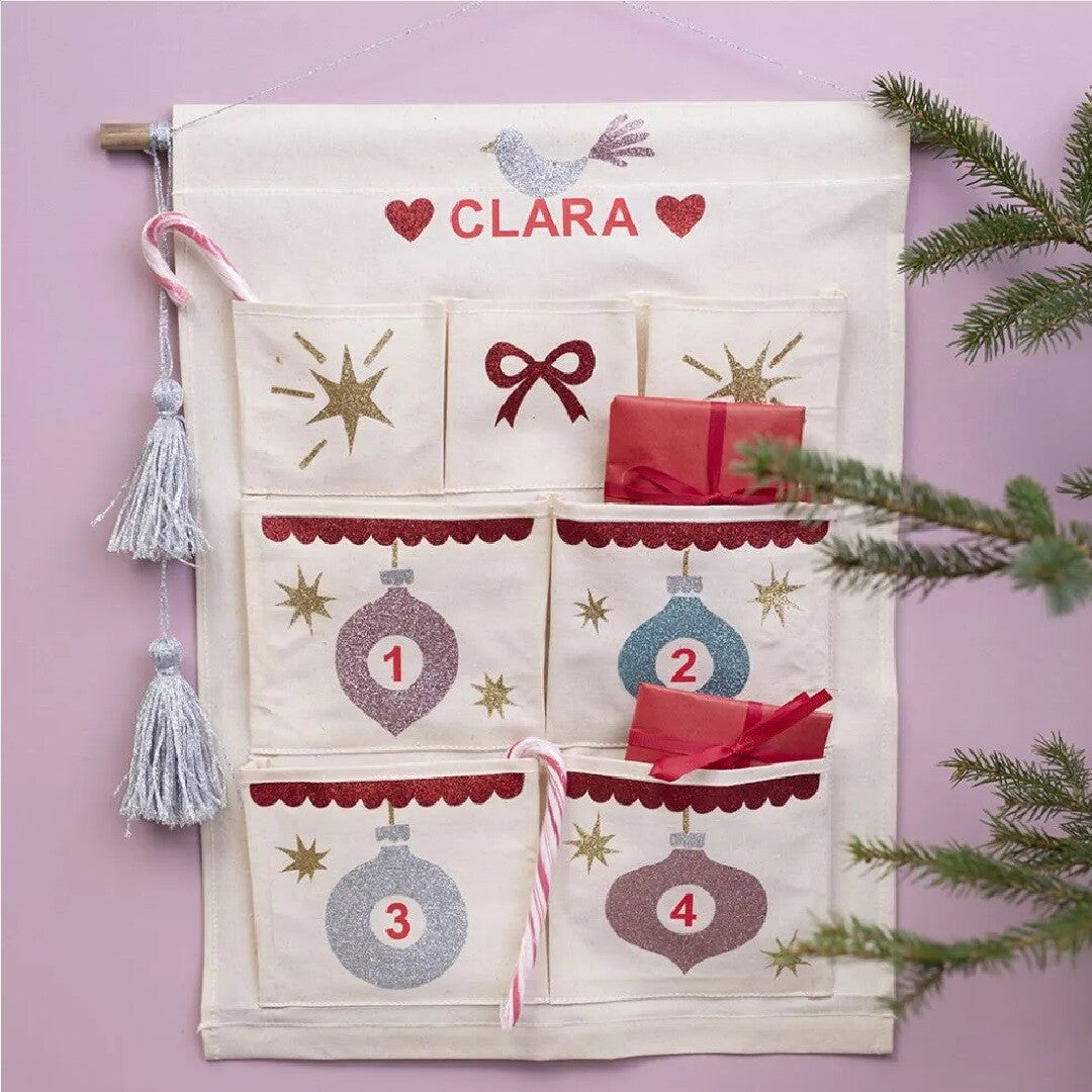 Creativ company beige canvas hangende organizer versierd als adventskalender met kerstballen, cijfers en de naam 'CLARA'.